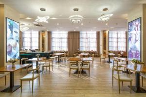 a restaurant with wooden tables and chairs and windows at GreenTree Eastern Yancheng Administration Center Hotel in Yancheng