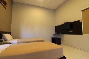 una camera d'albergo con due letti e una TV a schermo piatto di MANDARI HOTEL SINGARAJA a Singaraja
