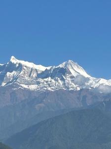 una montaña cubierta de nieve frente a un cielo azul en Holy mount home stay, en Astam