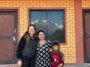 Dos mujeres y un niño de pie frente a una ventana en Holy mount home stay, en Astam