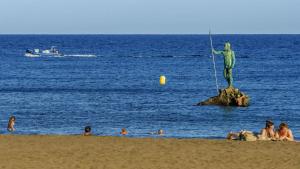 Eine Gruppe von Menschen am Strand mit einer Statue in der Unterkunft Suites Esencia Atlántica Mar, montaña y relax in Telde