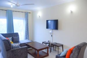 - un salon avec 2 chaises et une télévision murale dans l'établissement MTWAPA LUXURY Posta, à Mombasa