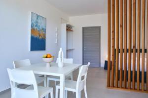 a white dining room with a white table and white chairs at Dara Holiday Apartments in Marsala