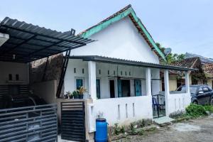 a white house with a gate and a fence at Hotel O Penginapan Indola Near Masjid Al Muhtadin in Muaradua