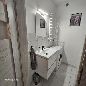 een witte badkamer met een wastafel en een spiegel bij Studio Człuchów Centrum in Człuchów