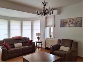 a living room with a couch and two chairs and a chandelier at Villa Bonifica in Riemst