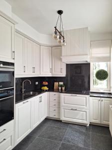 a white kitchen with white cabinets and a sink at Villa Bonifica in Riemst