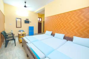2 bedden in een kamer met een stoel en een bureau bij Hotel Dreamline Teerth GH Near Temple # Kashi Temple - Restaurant # Free WIfi Service - Fully Air Conditioning Rooms# Best Premium Hotel In Varanasi in Varanasi