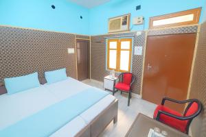 een slaapkamer met een bed en twee rode stoelen bij Hotel Dreamline Teerth GH Near Temple # Kashi Temple - Restaurant # Free WIfi Service - Fully Air Conditioning Rooms# Best Premium Hotel In Varanasi in Varanasi +15 foto's