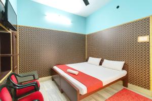 een kleine slaapkamer met een bed en een rode stoel bij Hotel Dreamline Teerth GH Near Temple # Kashi Temple - Restaurant # Free WIfi Service - Fully Air Conditioning Rooms# Best Premium Hotel In Varanasi in Varanasi