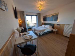 a hotel room with a bed and a desk with a chair at Juracîmes Appartements in Mijoux