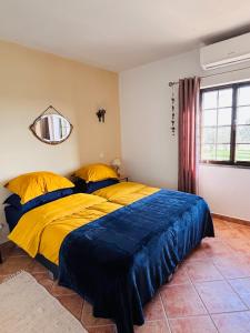 een slaapkamer met een bed met gele en blauwe lakens bij Quinta Monte da Azinheira in Amareleja