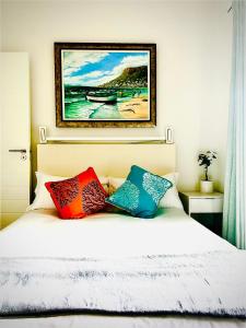 een slaapkamer met een bed met kleurrijke kussens erop bij KommRust in Kommetjie