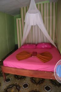 Fun Family Guest House n Jungle Tour في بوكيت لاوانج: سرير ذو ملاءات وردية اللون وعليه ربطة عنق