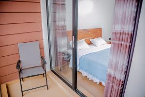 ein Schlafzimmer mit einem Bett und einem Stuhl in einem Zimmer in der Unterkunft Agasaro House Kigali in Kigali