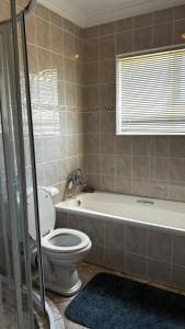 a bathroom with a toilet and a tub and a sink at Lilies and Leopards Holiday Home B & B in Mossel Bay +22 photos
