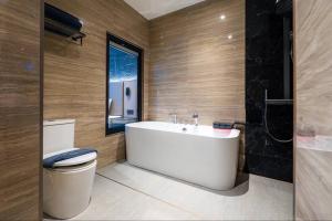 a bathroom with a tub and a toilet and a window at Tonnam pool villa in Nong Prue