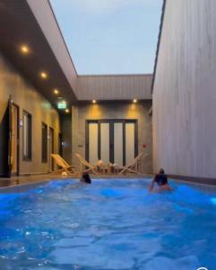 two people swimming in a large swimming pool at Tonnam pool villa in Nong Prue