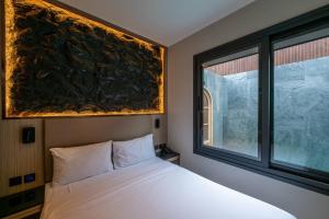 a bedroom with a bed and a large window at Tonnam pool villa in Nong Prue