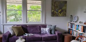 a purple couch in a living room with two windows at Kipsie Cottage - Point Lonsdale in Point Lonsdale