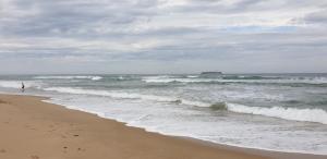 a person standing on the beach near the ocean at Kipsie Cottage - Point Lonsdale in Point Lonsdale