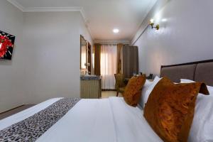 Un dormitorio con una gran cama blanca con almohadas. en Nokras SilverOak Hotel, Embu, en Embu