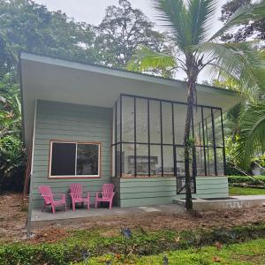 a small house with pink chairs and a palm tree at La Rana De Cahuita in Cahuita
