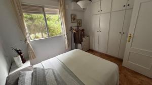 ein weißes Schlafzimmer mit einem Bett und einem Fenster in der Unterkunft Bungalow muy cerca de la playa in Santa Pola + 17 Fotos