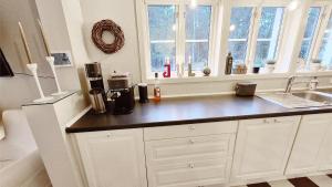 een keuken met witte kasten, een wastafel en ramen bij Brotorpet in Torsebo +37 foto's