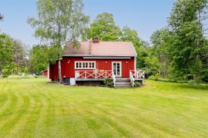 een rood huis in een veld met een grote tuin bij Brotorpet in Torsebo