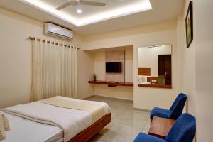 a bedroom with a bed and two blue chairs at Hotel Rajpurush in Kolhapur