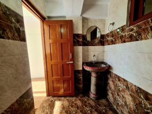 a bathroom with a sink and a wooden door at Narkanda Heights Rooms in Nārkanda