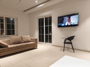 a living room with a couch and a tv on a wall at Palms Villa in Dharmpura