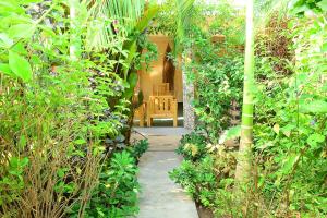 Un camino a través de un jardín con una silla al fondo. en Mbilimbi Malazi, en Zanzíbar