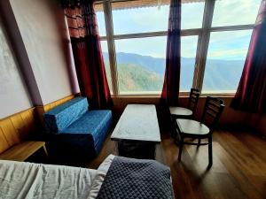 a room with a large window and a bed and chair at Narkanda Heights Rooms in Nārkanda