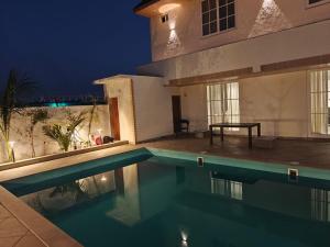 a swimming pool in front of a house at night at Palms Villa in Dharmpura +41 photos