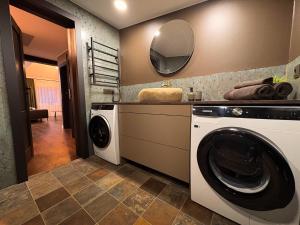 a laundry room with a washing machine and a mirror at Telšiai Modern Central Apartments in Telšiai