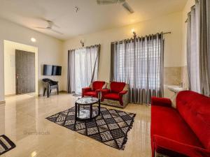 uma sala de estar com um sofá vermelho e cadeiras vermelhas em Coastal Green resort em Mahabalipuram