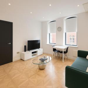 uma sala de estar com um sofá, uma TV e uma mesa em Leeds Central Cosy 1BD Flat 10 mins to Station! em Leeds