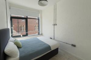 um quarto com uma cama e uma janela grande em Leeds Central Cosy 1BD Flat 10 mins to Station! em Leeds
