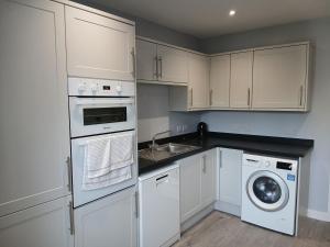 ハイクリフにあるsilver wayのキッチン(白いキャビネット、洗濯機、乾燥機付)