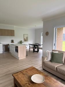 una sala de estar con un sofá y una mesa en Family Holiday Home Ulladulla, en Ulladulla