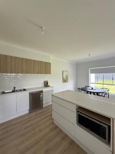 Una cocina con gabinetes blancos y una mesa en ella. en Family Holiday Home Ulladulla, en Ulladulla