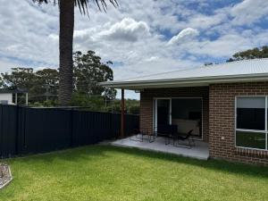 una casa di mattoni con due sedie e una recinzione di Family Holiday Home Ulladulla a Ulladulla