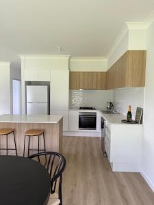 Una cocina con gabinetes blancos y una mesa y sillas. en Family Holiday Home Ulladulla, en Ulladulla 5 fotos más