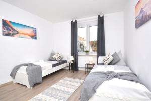 a white bedroom with two beds and a window at NÜ06-BP - Apartment for companies in Zirndorf