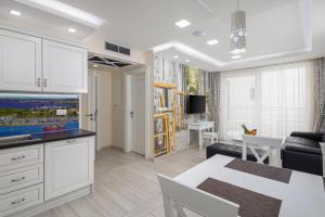 a kitchen with white cabinets and a living room at Villa Jakov Apartments II in Promajna