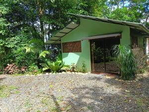 a green building with a door in a yard at Breezes Ecolodge in San Ramón
