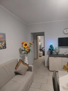 una sala de estar con sofá y un jarrón de flores en Girasole, en Alessandria