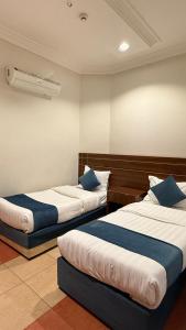 a room with two beds with blue pillows at Distinctive Palace - القصصر المميز للشقق المفروشه in Abha